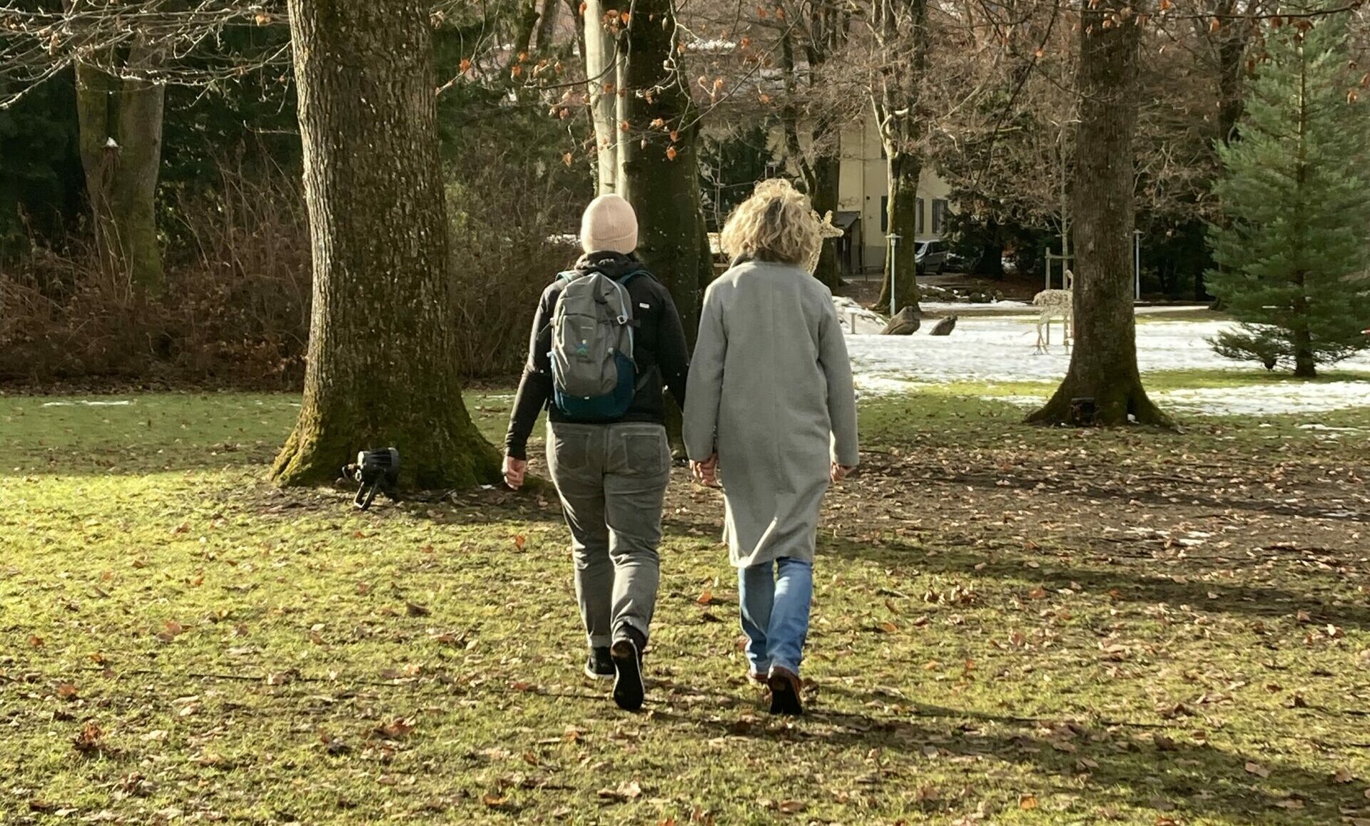 Zwei Menschen gehen auf einer Wiese spazieren.